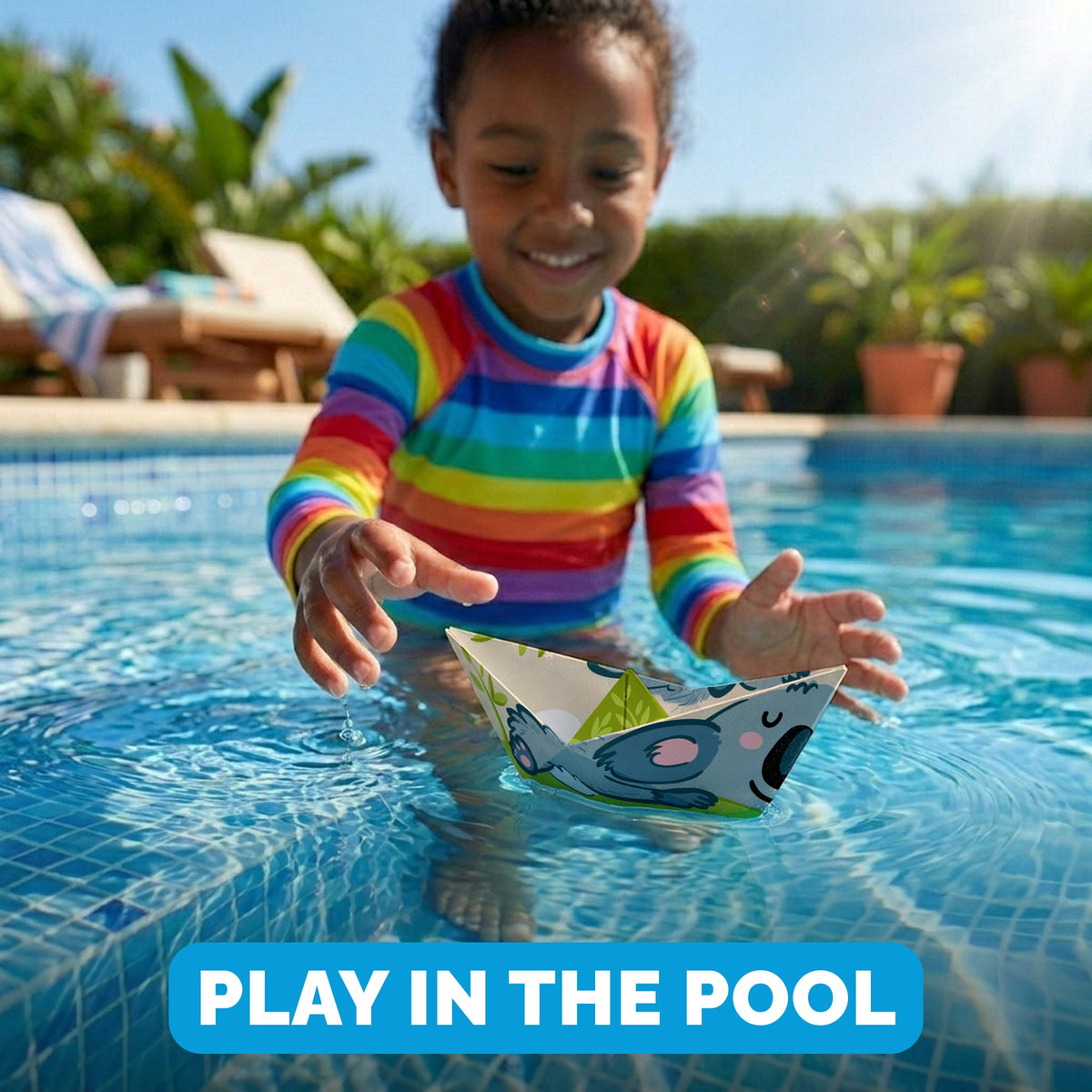 Child playing with a WOYS Tropics paper boat in the pool